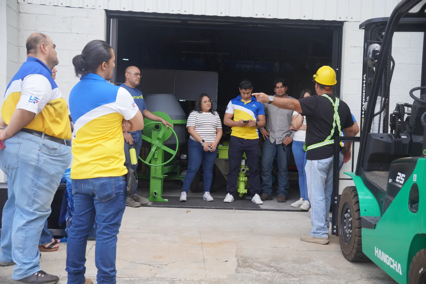 Instructor con casco y chaleco dando la charla inicial de seguridad a un grupo de alumnos