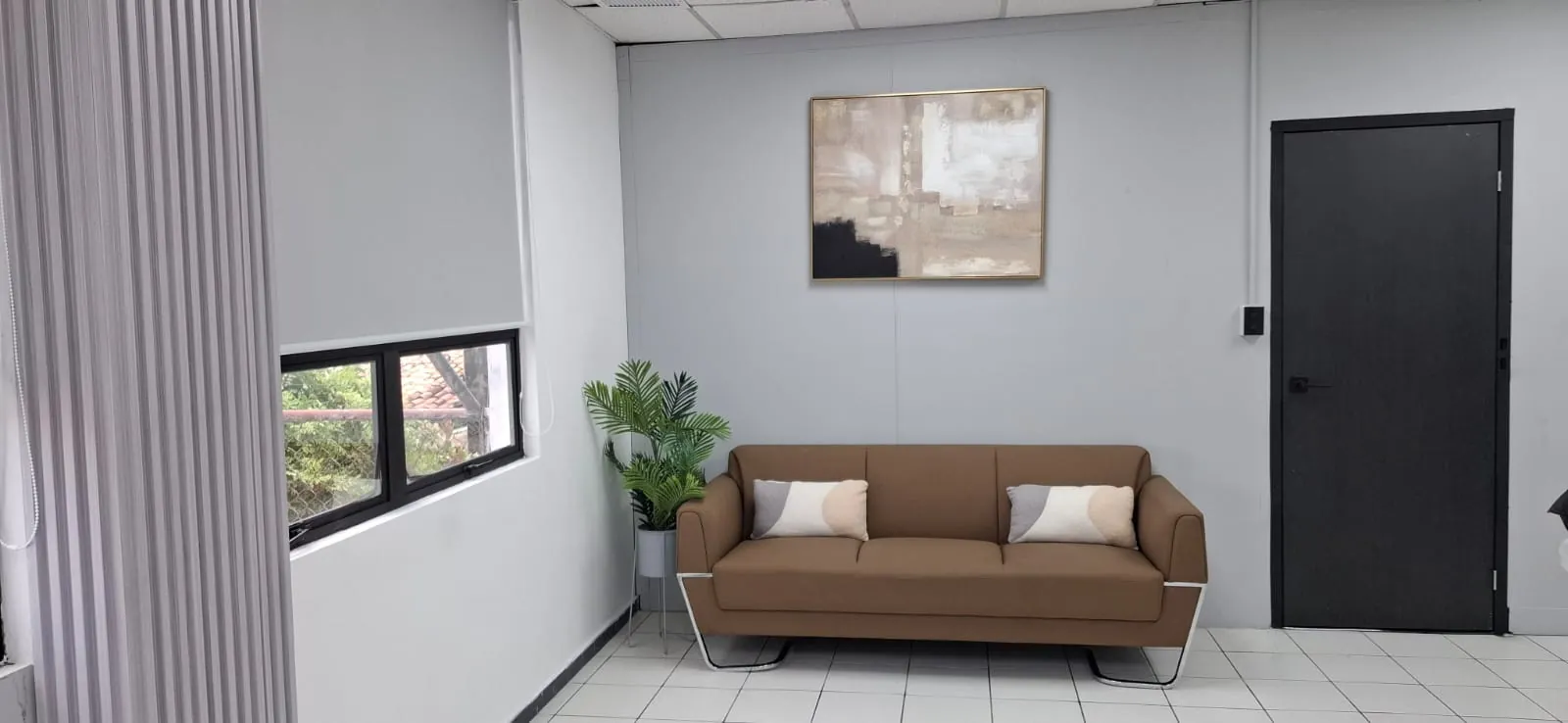 Sala de espera con sofá de tres plazas y planta