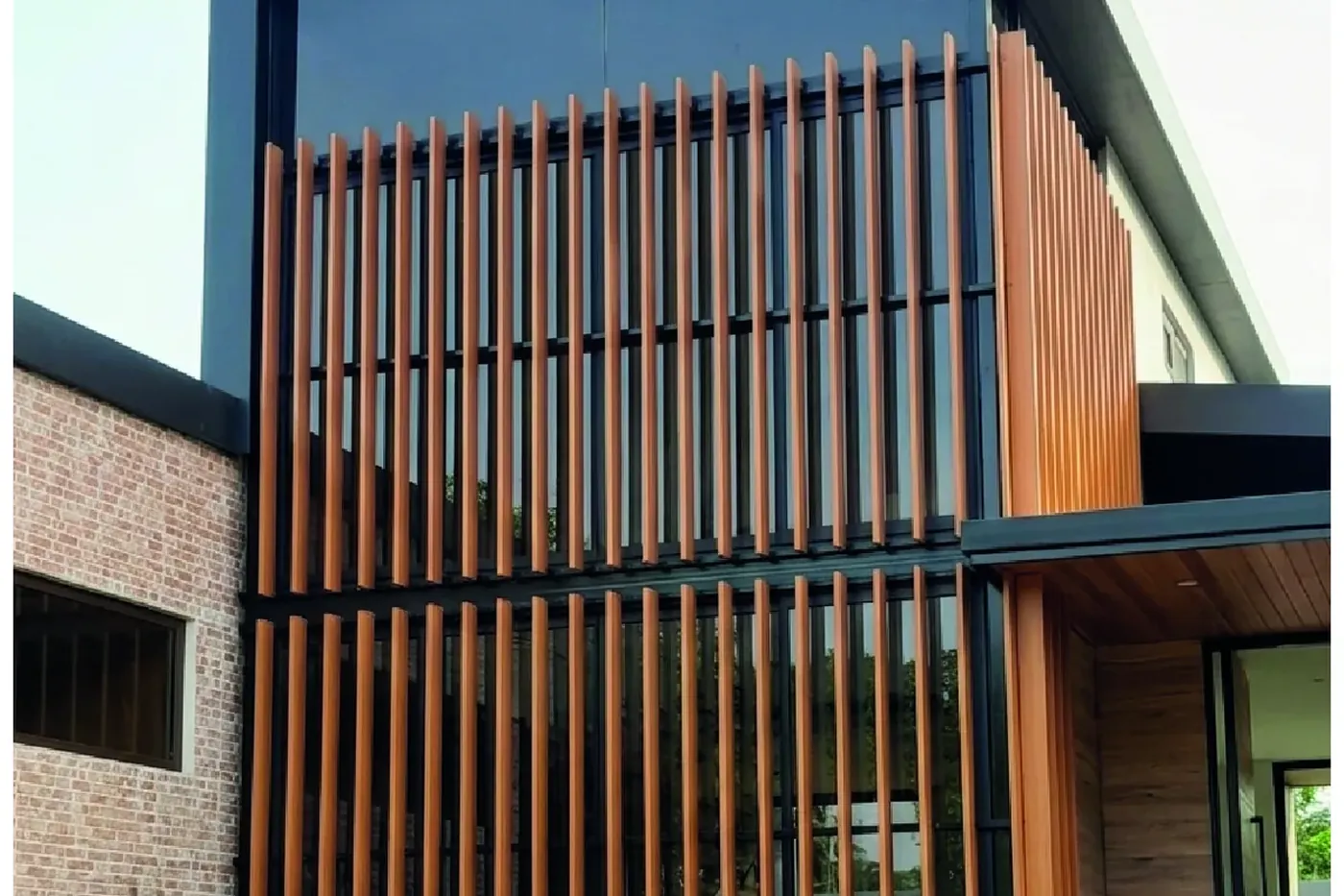 Façade with vertical wood-look slats in front of a brick wall