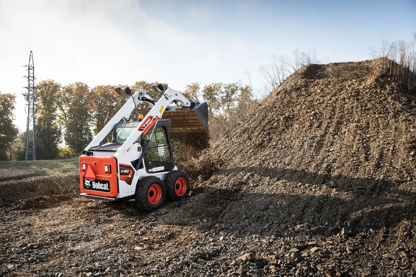 Bobcat skid-steer loader moving soil next to a stockpile