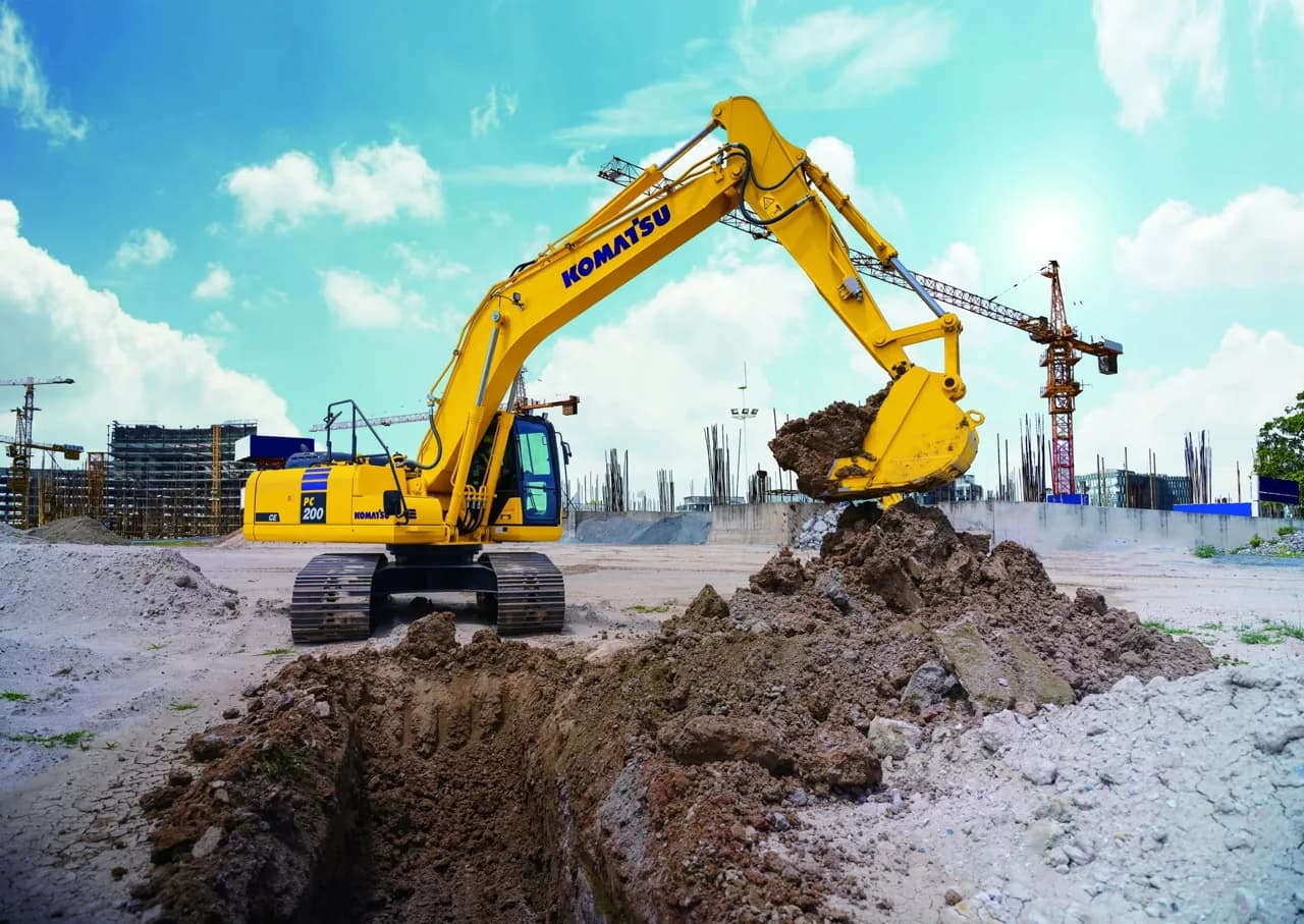 Excavadora Komatsu PC200 excavando en obra de edificación con grúas torre